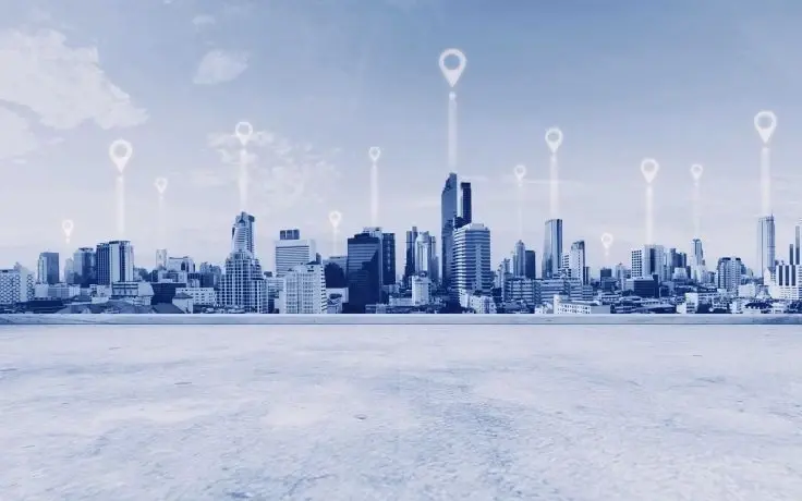 A blue-toned cityscape with skyscrapers under a cloudy sky, overlaid with several glowing location pin icons.