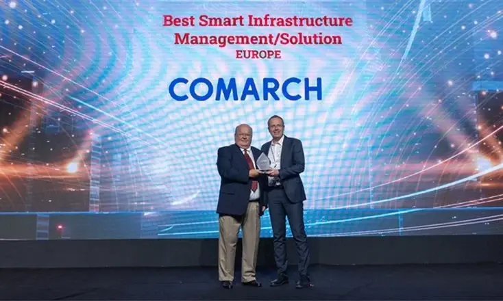 Two Comarch representatives standing on stage, holding an award for "Best Smart Infrastructure Management/Solution Europe."
