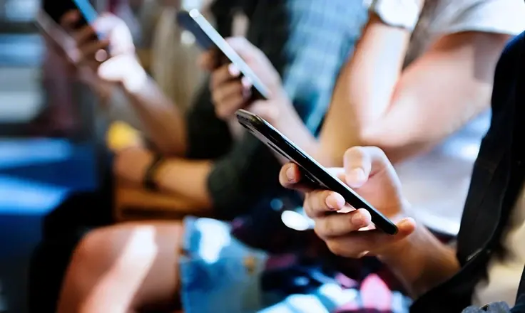 A line of people holding smartphones in their hands.