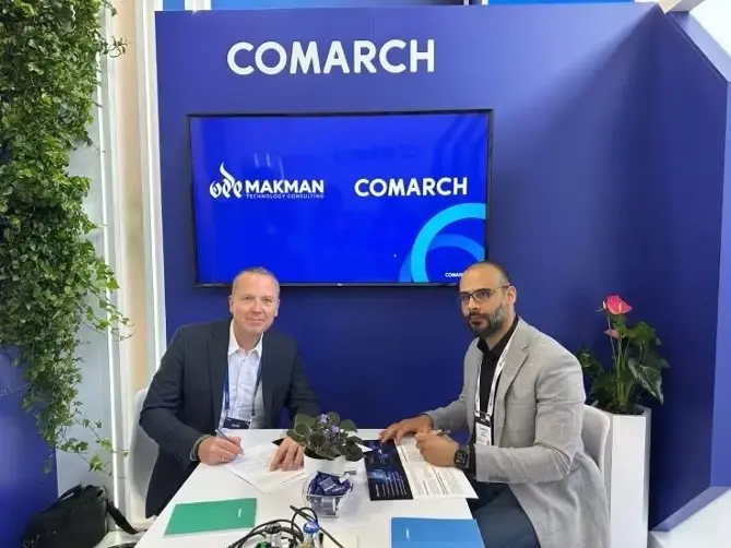 Makman Technology Consulting and Comarch Communications representatives signing a contract at a table.