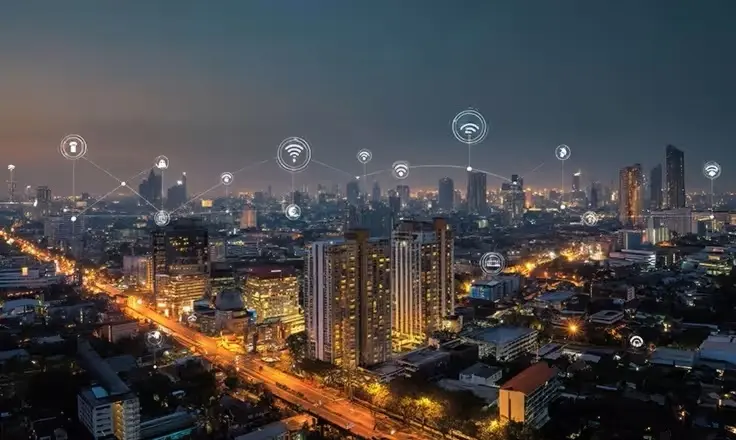 Aerial night view of a glowing city skyline with lines connecting glowing Wi-Fi and IoT icons above the buildings.