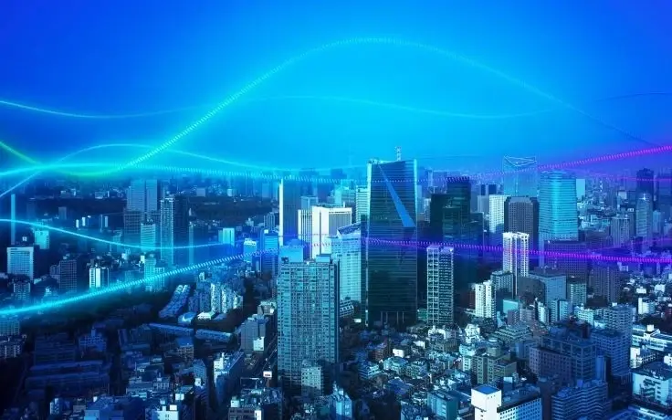 Aerial view of a modern cityscape skyline with glowing blue and green digital data streams.