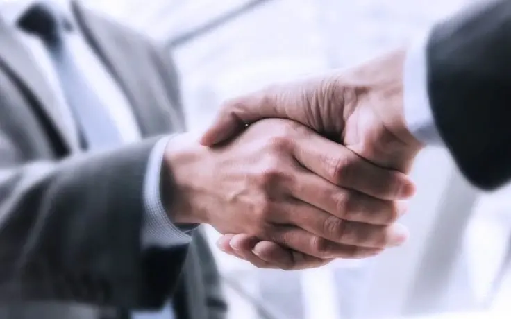 A handshake between two business professionals in suits.