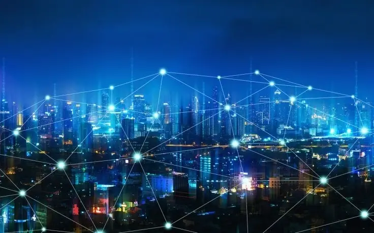 A night cityscape with illuminated buildings overlaid with a network of glowing white nodes and connecting lines.