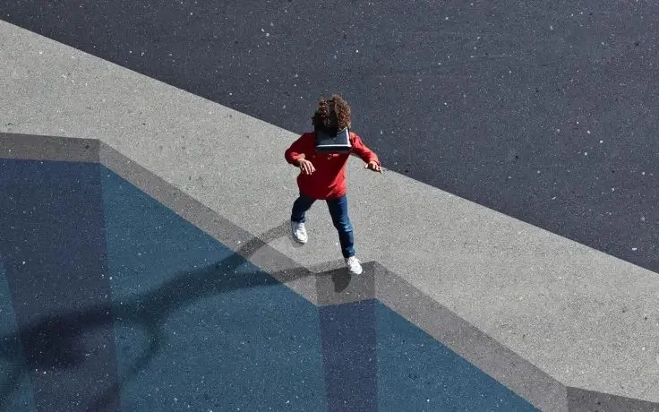 A high-angle view of a person wearing a VR headset and walking across a large geometric pattern on the ground.