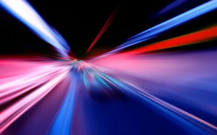 Abstract long-exposure photograph featuring vibrant streaks of blue, pink, and white light against a dark background.