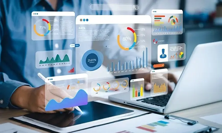 A person in a blue shirt writes on a tablet as virtual business data dashboards, charts, and graphs float around them.