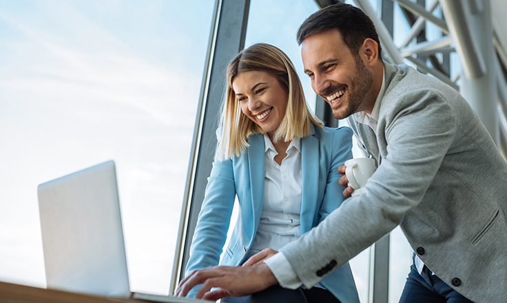 Men and woman standing in front of a laptop